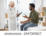 Medical specialist adjusts composition of drugs looking at electronic history of patient in exam room. Bearded man receiving chemotherapy looking at nurse with tablet examining condition of patient.