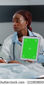 Medical Specialist Vertically Holding Green Screen On Tablet In Hospital Ward. Physician And Sick Person Looking At Gadget Display With Chroma Key And Isolated Mockup Background.