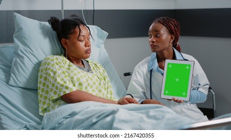 Medical Specialist Vertically Holding Green Screen On Tablet In Hospital Ward. Physician And Sick Person Looking At Gadget Display With Chroma Key And Isolated Mockup Background.