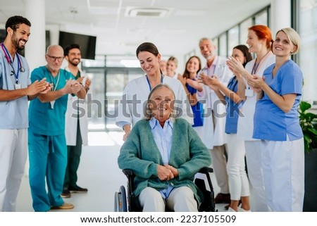 Medical staff clapping to senior patient who recovered from serious illness.