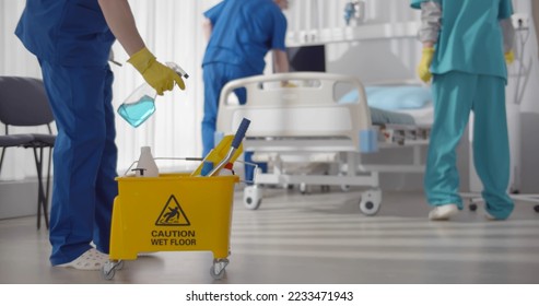 Medical staff doing disinfection and cleaning in intensive care unit of clinic. Team of nurses in uniform and safety mask cleaning hospital ward during covid-19 epidemic