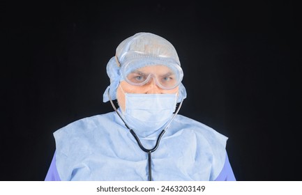 Medical staff. Portrait of serious doctor in protective mask, goggles and disposable surgical cap with stethoscope. Hospital worker in medical uniform. Male nurse in sterile mask and scrubs in clinic - Powered by Shutterstock