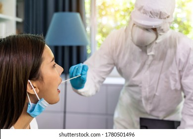 Medical Staff With PPE Suit Test Coronavirus Covid-19 To Asian Woman By Throat Swab At Home. New Normal Healthcare Service At Home And Medical Delivery Concept.