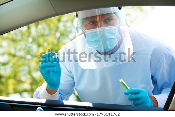 Medical staff with PPE suit testing patient at a\
Covid-19 drive thru by throat swab. Health care drive thru service\
and medical concept