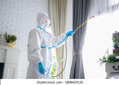 A Medical Staff In PPE Suit Is Using Disinfectant Spray In Living Room, Covid-19 Protection , Disinfection Concept .