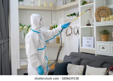 A Medical Staff In PPE Suit Is Using Disinfectant Spray In Living Room, Covid-19 Protection , Disinfection Concept .