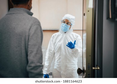 Medical Staff In PPE Suit Visit Patient Home During Coronavirus COVID-19 Spreading. Senior Male Opening The House Door To A Health Professional On A Home Visit. Pandemic Crisis, Outbreak.