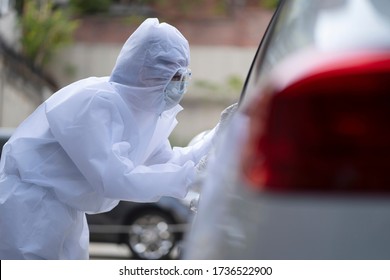 Medical staff in protective suit collecting sample for covid-19 at drive through - Powered by Shutterstock