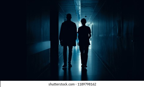 Medical Staff Silhouettes Walk in Dark Part of the Hospital Corridor.