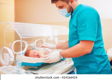 medical staff taking care of newborn baby in infant incubator