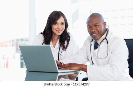 Medical Staff Working In Front Of A Grey Laptop While Sitting At The Desk