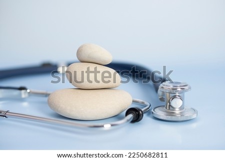 medical stethoscope and Balanced Stones on a blue background and copy space for insurance planning, protection and safety concept of balance and reliability of medical health insurance.