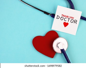 Medical Stethoscope, Red Healthy Heart And Thank You Doctor Text On Blue Background. Concept Of Gratitude To Health Workers During A Pandemic