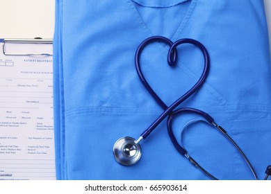Medical stethoscope twisted in heart shape lying on patient medical history list and blue doctor uniform closeup - Shutterstock ID 665903614