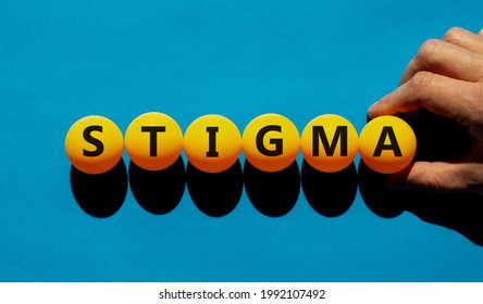 Medical and stigma symbol. The concept word 'stigma' on orange table tennis balls on a beautiful blue background. Doctor hand. Medical, psychological, religion and stigma concept.