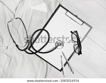 Medical still life. Blank clipboard, stethoscope, glasses, thermometer and pen. Flat lay.