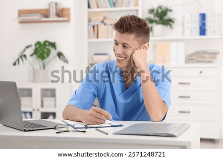 Medical student taking notes while studying at table indoors