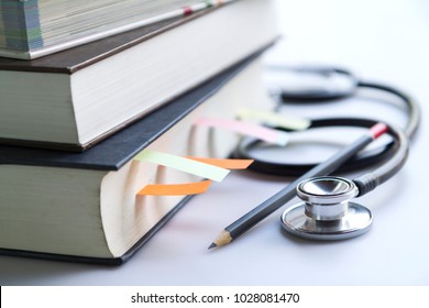 Medical student textbooks with pencil and multicolor bookmarks and stethoscope isolated on white - Shutterstock ID 1028081470