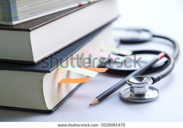Medical student textbooks\
with pencil and multicolor bookmarks and stethoscope isolated on\
white