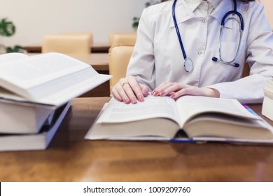 a medical student for textbooks. The study of surgery by a beautiful girl in the library. Nurse. copy space