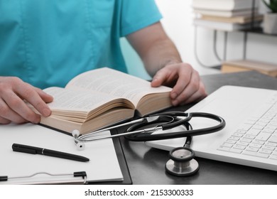 Medical student in uniform studying at table indoors, closeup - Powered by Shutterstock