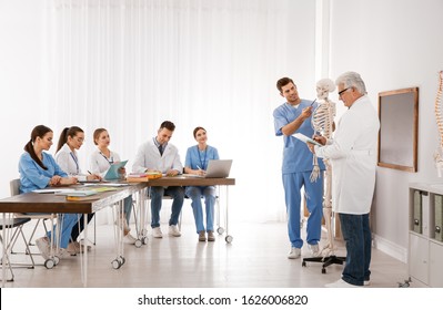 Medical students and professor studying human skeleton anatomy in classroom - Powered by Shutterstock