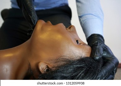 Medical Stuff In A Black Gloves Performing 'clear And Open Tha Airway' Head Tilt - Chin Lift On A Simulation Mannequin Dummy During Basic Life Support To Control The Airway.  Medical Manipulation
  