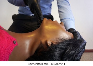 Medical Stuff In A Black Gloves Performing 'clear And Open Tha Airway' Head Tilt - Chin Lift On A Simulation Mannequin Dummy During Basic Life Support To Control The Airway.  Medical Manipulation
  