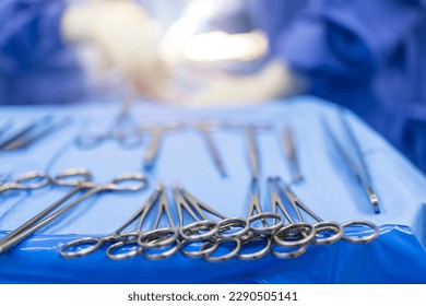 A medical or surgical instrument for surgery inside the operating theatre with blur team of doctors in blue gown background.Surgical clamps for a surgeon on the blue tray.Blur background with light. - Powered by Shutterstock