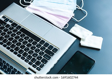 Medical surgical masks lie on a laptop on a black table with a phone and antibacterial wipes. Quarantine mobile workplace concept against covid-19 epidemic