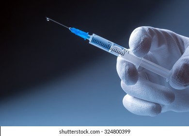 Medical syringe with needle in hand doctor. At the end of the needle drop of liquid