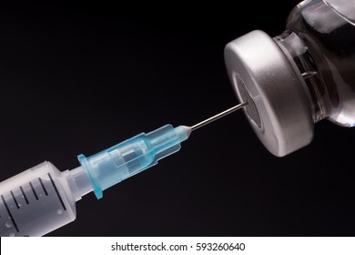Medical syringe with the needle in the vial. Isolated on black background