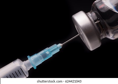 Medical Syringe With The Needle In The Vial. Isolated On Black Background