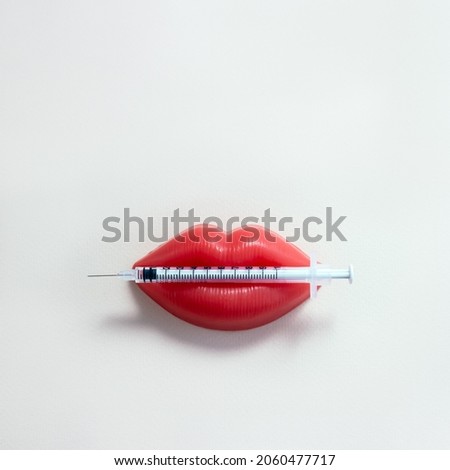 Medical syringe and plasticine lips. Lip injection creative concept. Selective focus, square orientation