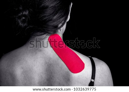 Medical taping for neck and shoulder blade pain relief showed on young model isolated on black background.