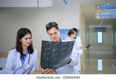 Medical teacher and interns analyzing the x-ray results of the patient's brain. before major surgery in the operating room - Powered by Shutterstock