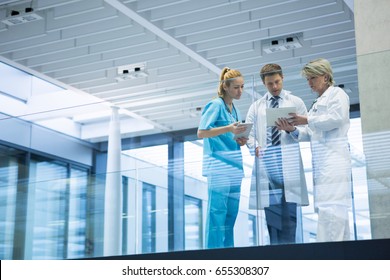 Medical Team Discussing Over Digital Tablet In Corridor At Hospital