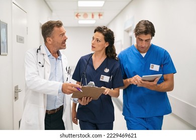 Medical team discussing medical report while walking at work. Mature doctor and surgeon working on digital tablet with nurse and walking in hospital. Head physician working with his medical staff. - Powered by Shutterstock