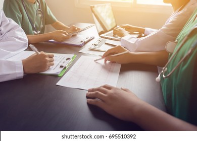 medical team having a meeting with doctors in white lab coats and surgical scrubs seated at a table discussing a patients records,success medical health care, Medicine doctor's working concept 