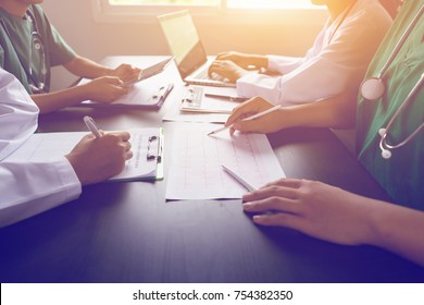 medical team having a meeting with doctors in white lab coats and surgical scrubs seated at a table discussing a patients records,success medical health care, Medicine doctor's working concept