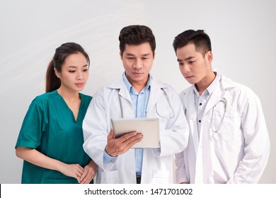 Medical Team Includes Doctors And Nurse Looking At An Ipad/tablet Computer Together