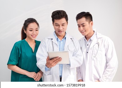 Medical Team Includes Doctors And Nurse Looking At An Ipad/tablet Computer Together