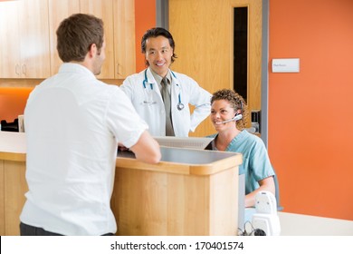 Medical Team With Male Patient At Reception Desk In Hospital