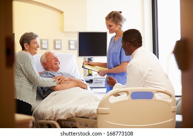 Medical Team Meeting With Senior Couple In Hospital Room