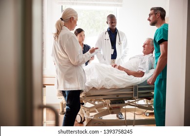 Medical Team On Rounds Meeting Around Bed Of Senior Male Patient