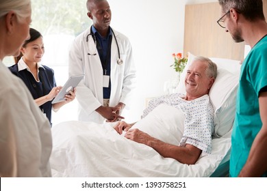 Medical Team On Rounds Meeting Around Bed Of Senior Male Patient