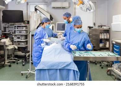 Medical Team Performing Operation. Group Of Surgeon At Work In Operating Theatre Toned In Blue. Doctor Operation In Operation Room At Hospital Concept For Insurance Advertising.