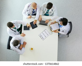 Medizinisches Team sitzt und diskutiert am Tisch, Draufsicht