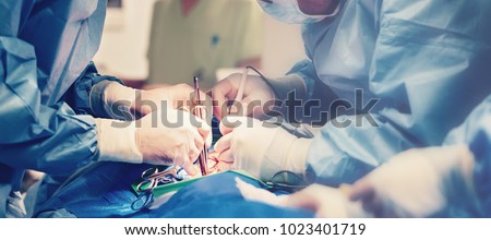 Medical team of surgeons in hospital doing minimal invasive surgical interventions. Surgery operating room with electrocautery equipment for cardiovascular emergency surgery center.