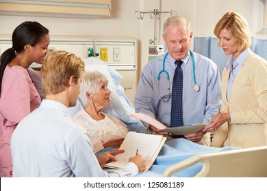 Medical Team Visiting Senior Female Patient In Bed